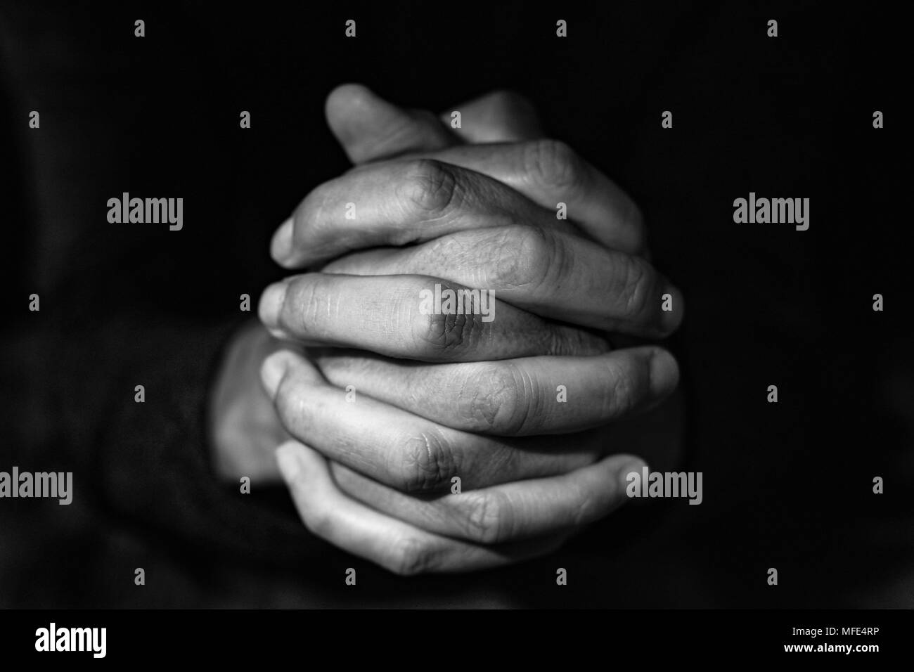 Nahaufnahme der Hände eines jungen kaukasischen Mann mit seiner gefalteten Händen, in Schwarz und Weiß Stockfoto