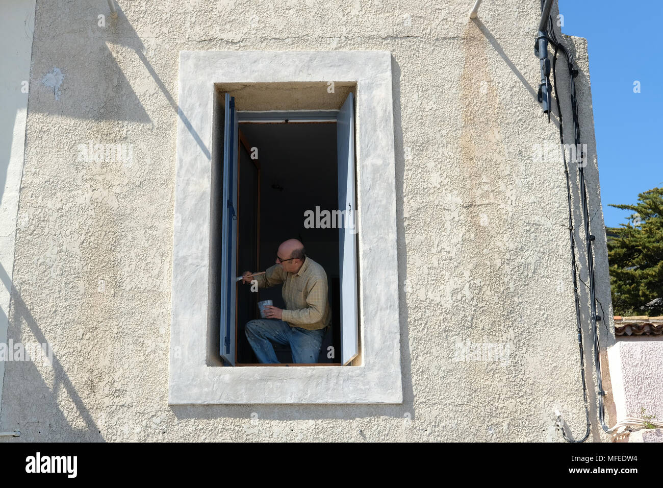 Ein Mann Malerei seine Fensterläden in Frankreich. Stockfoto