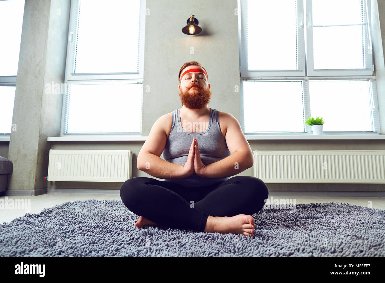 Eine lustige Fetten bärtigen Mann im Sport Kleidung Yoga im Zimmer. Stockfoto