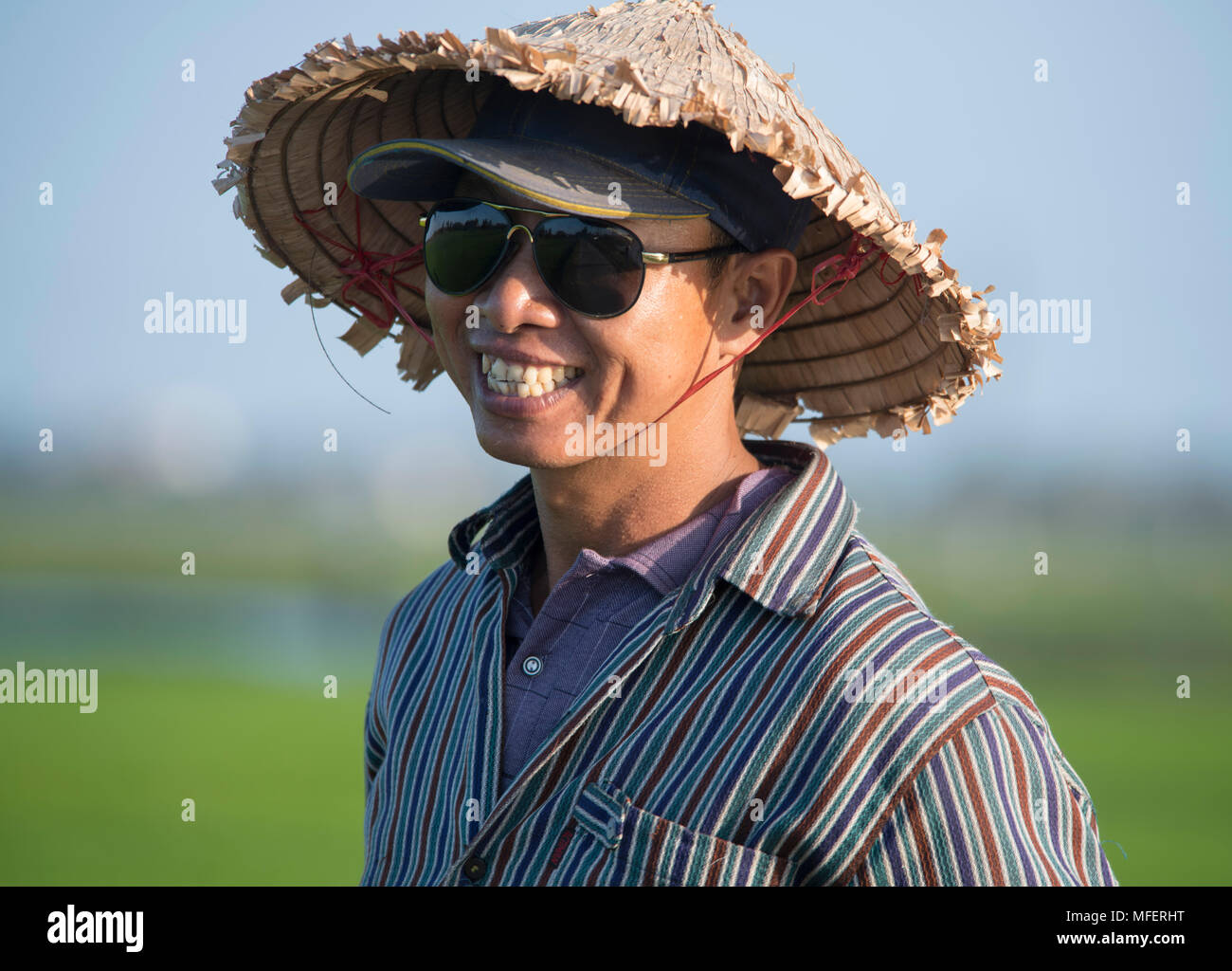 Eine vietnamesische Mann mit einem traditionellen Strohhut und Baseball Cap in der Nähe von Hoi An, Provinz Quang Nam, Vietnam, Südostasien Stockfoto