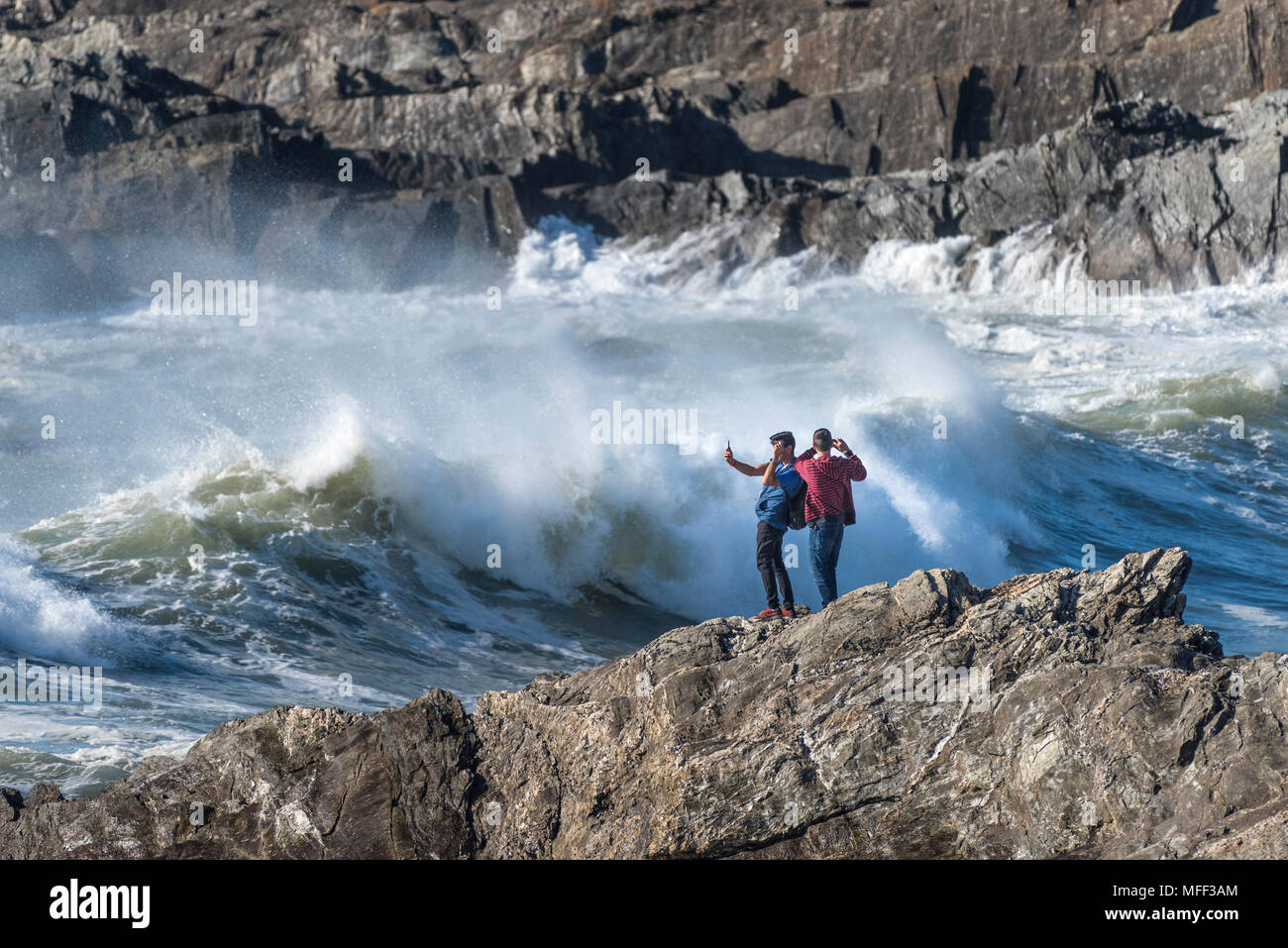 Touristen stehen auf Felsen die Fotografie als große mächtige Wellen brechen am Ufer an wenig Fistral in Newquay Cornwall. Stockfoto