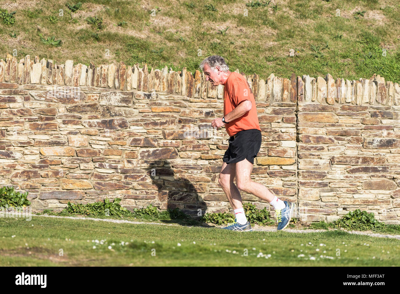 Eine ausgereifte Läufer joggen über einen Fußweg in Fistral in Newquay in Cornwall. Stockfoto