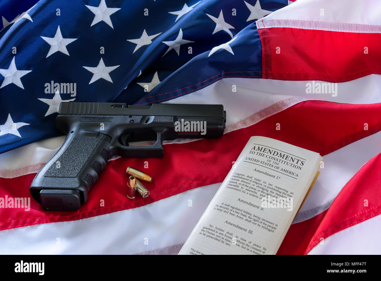 Die zweite Änderung und Waffenbesitz in den USA, Konzept. Pistole, Aufzählungszeichen und die amerikanische Verfassung auf der USA-Flagge. Stockfoto