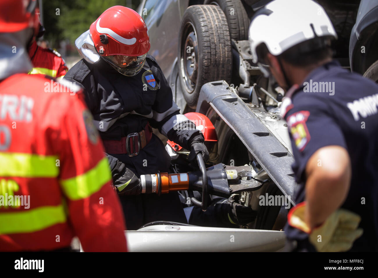 Rescue Feuerwehrleute und Sanitäter nehmen an einem aus verunfallten Fahrzeugen an einen Bohrer Car Crash Site Stockfoto