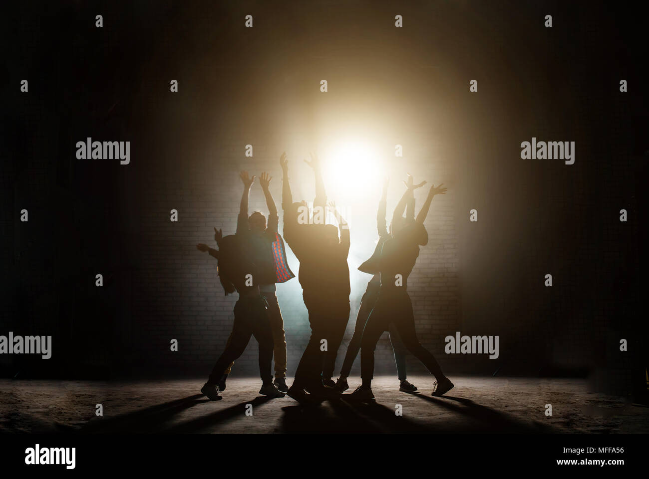 Junge Menschen stehen mit erhobenen Händen. zusammen beten und in die Sonne. Einfluss der Sekte Gottesdienst Licht. Anbetung der Sonne Sonne Kult. Tanz Film Stockfoto