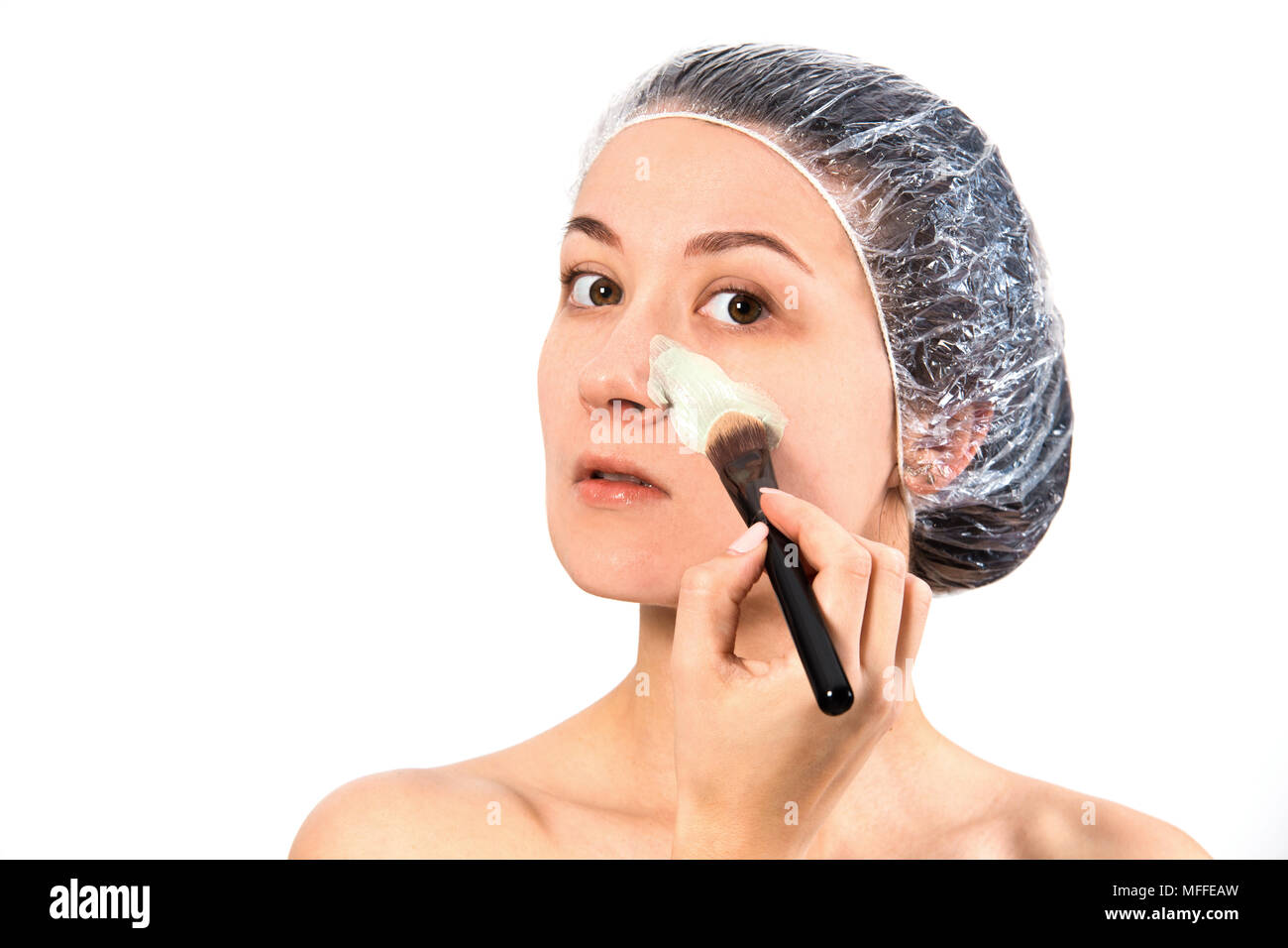 Hautpflege. Frau Anwendung reinigende Maske auf Gesicht haut auf wgite Hintergrund isoliert. Stockfoto