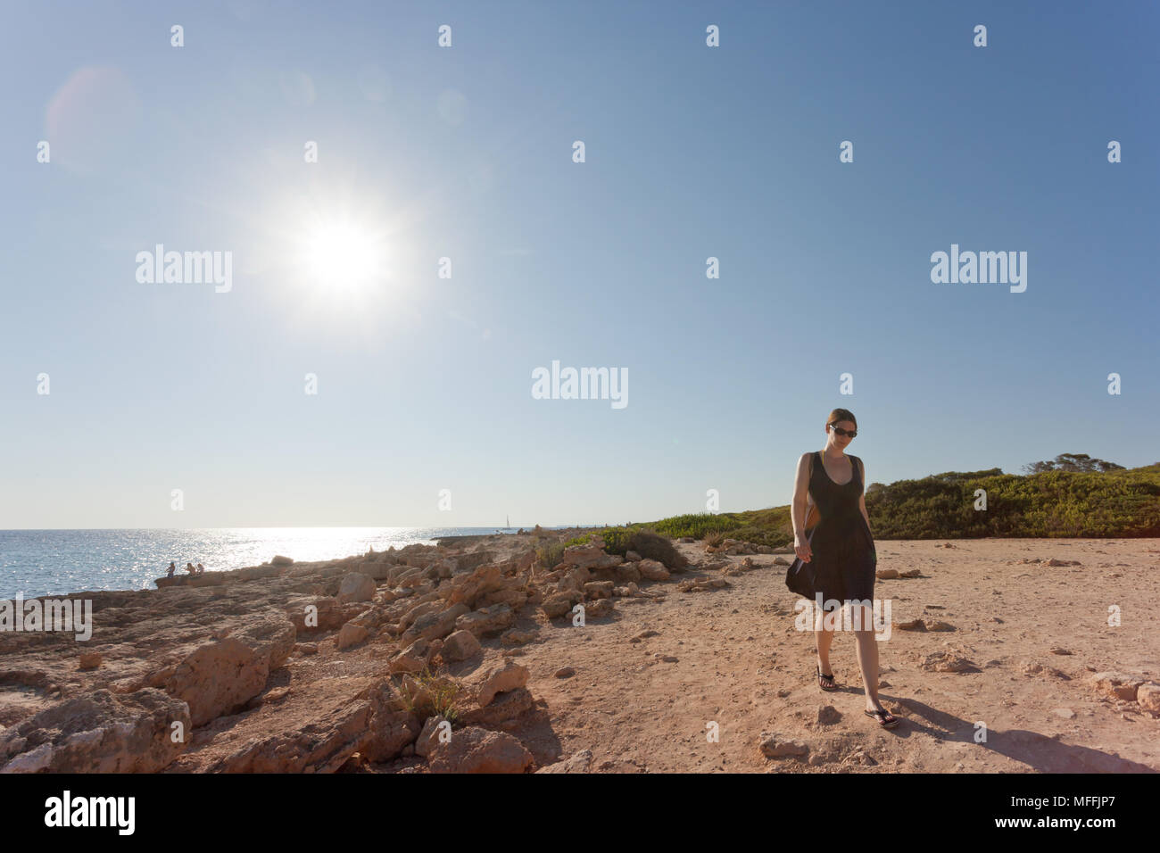 Cap de Ses Salines, Mallorca, Spanien - eine junge Frau, die sich für einen Spaziergang am Strand von Ses Salines Stockfoto