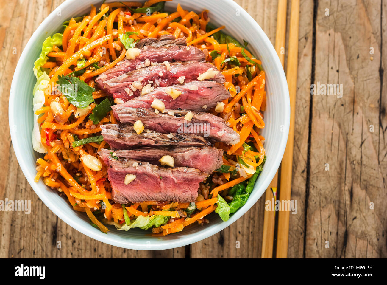 Bangkok Rindfleisch. Rindfleisch mit rotem Reis, geriebenen Karotten, Baby gem Salat, Erdnüsse & nam Jim Dressing Stockfoto