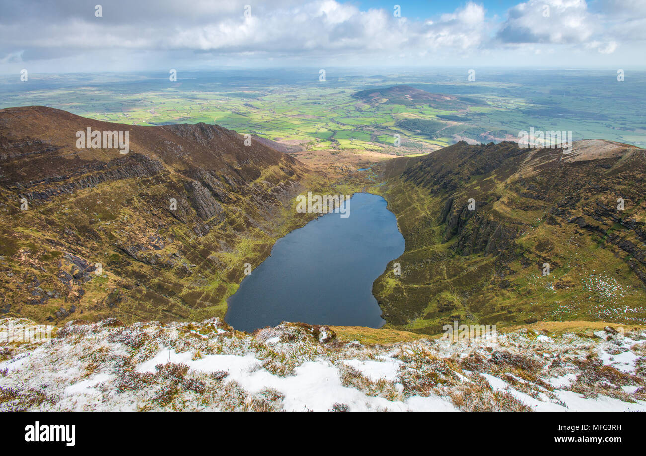 Luftbild von der Oberseite der Bergkamm mit Blick auf den blauen See und Gletscher, Horseshoe Valley im Süden Irlands. Schnee, Ländereien und die Küste. Stockfoto