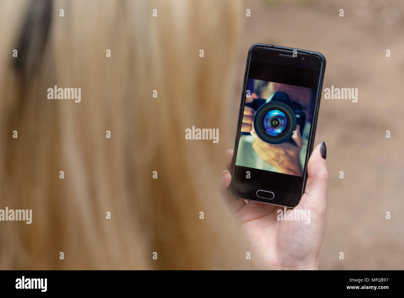 Die Hand hält das Telefon mit einem Foto des Fotografen auf dem Bildschirm. Stockfoto