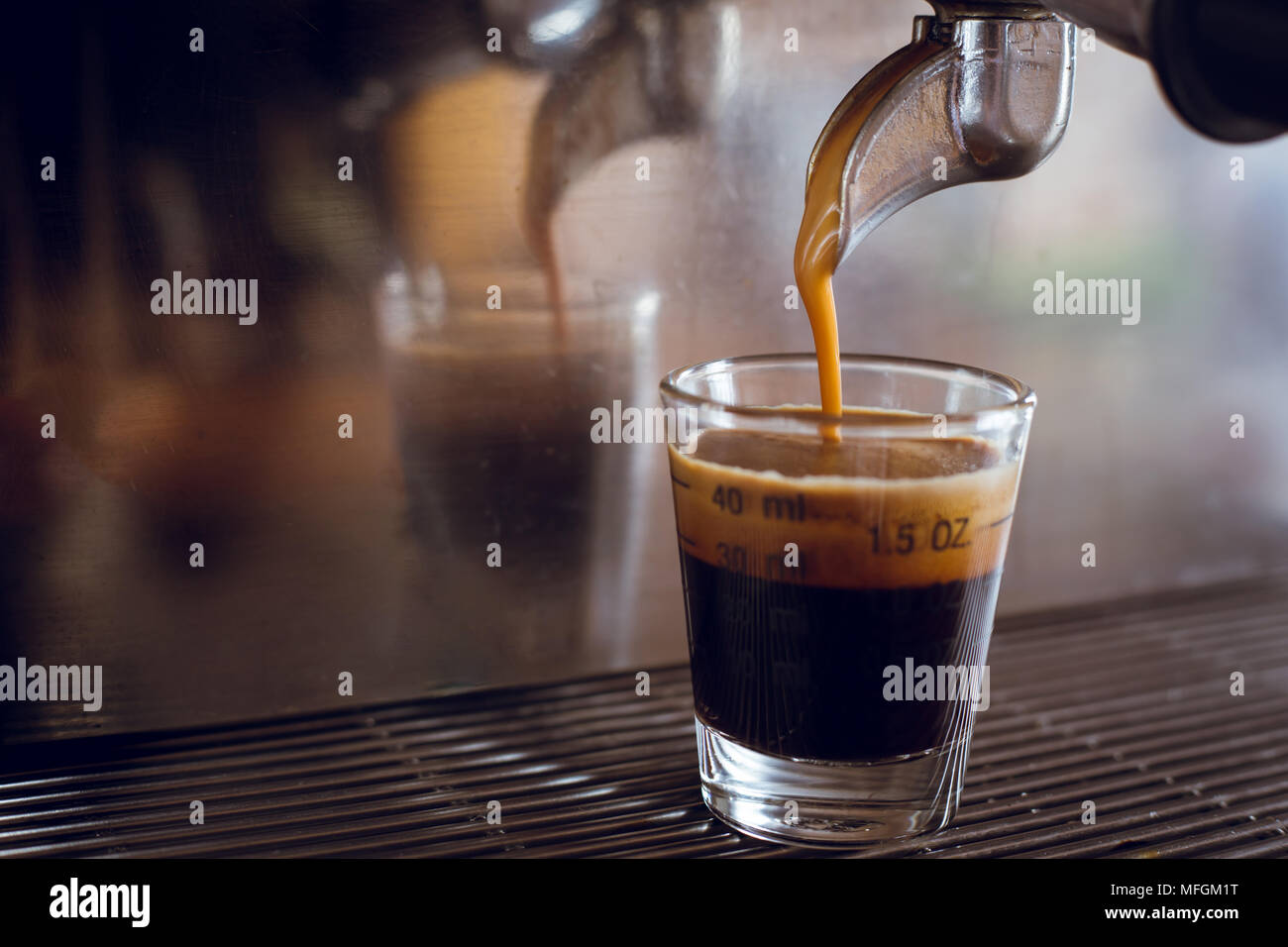 Professionelle Espressomaschine gießen starke suchen frischen Kaffee in eine Maßnahme Glas Schale Stockfoto