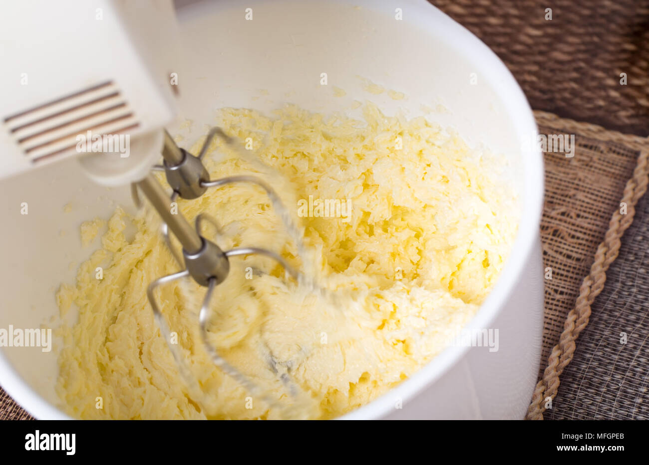 Das Mischen von Butter mit Zucker in weiße Schüssel zum Backen von Kuchen. Am Tisch als Hintergrund. Stockfoto