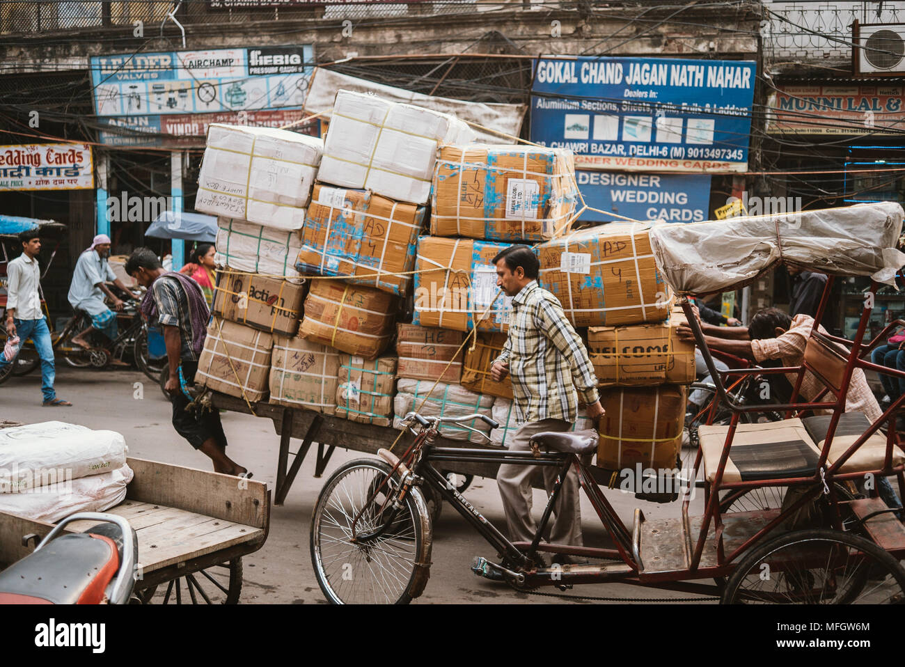 Männer treibt einen Wagen von Boxen auf einer belebten Straße in Delhi, Indien während der Hauptverkehrszeiten. Stockfoto