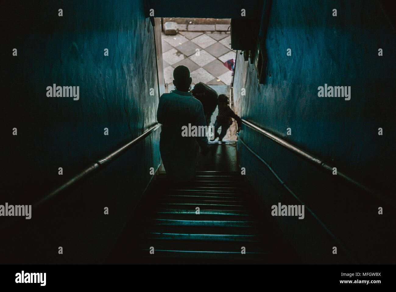 Arabischen muslimischen Mann verlassen dunkle Treppe auf überfüllten Straße in Delhi in Indien Stockfoto
