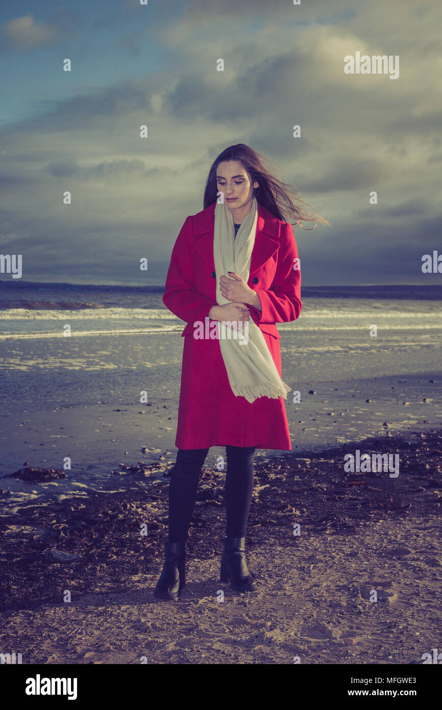 Frau in der roten Jacke an einem Strand. Stockfoto