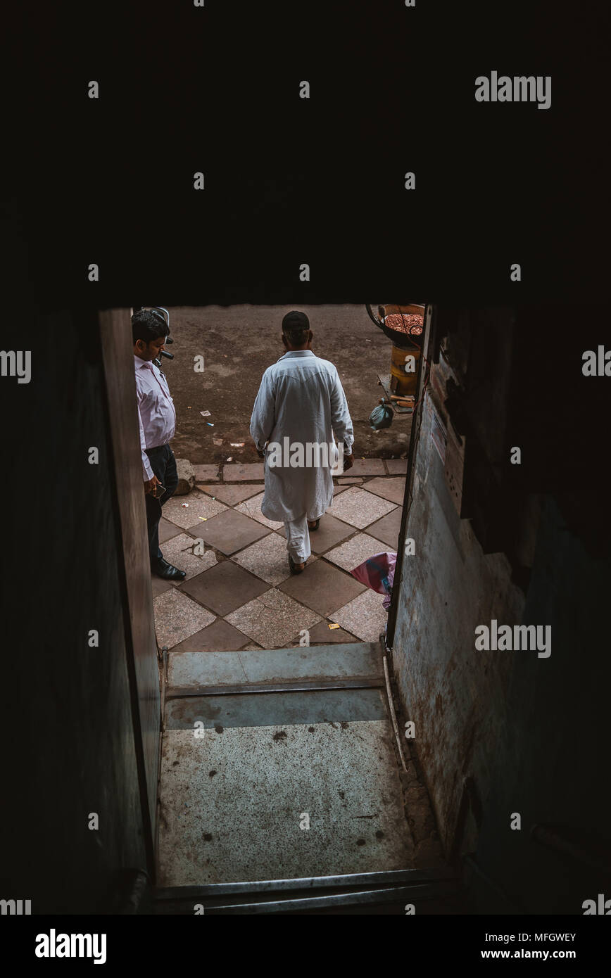 Arabischen muslimischen Mann verlassen dunkle Treppe auf überfüllten Straße in Delhi in Indien Stockfoto