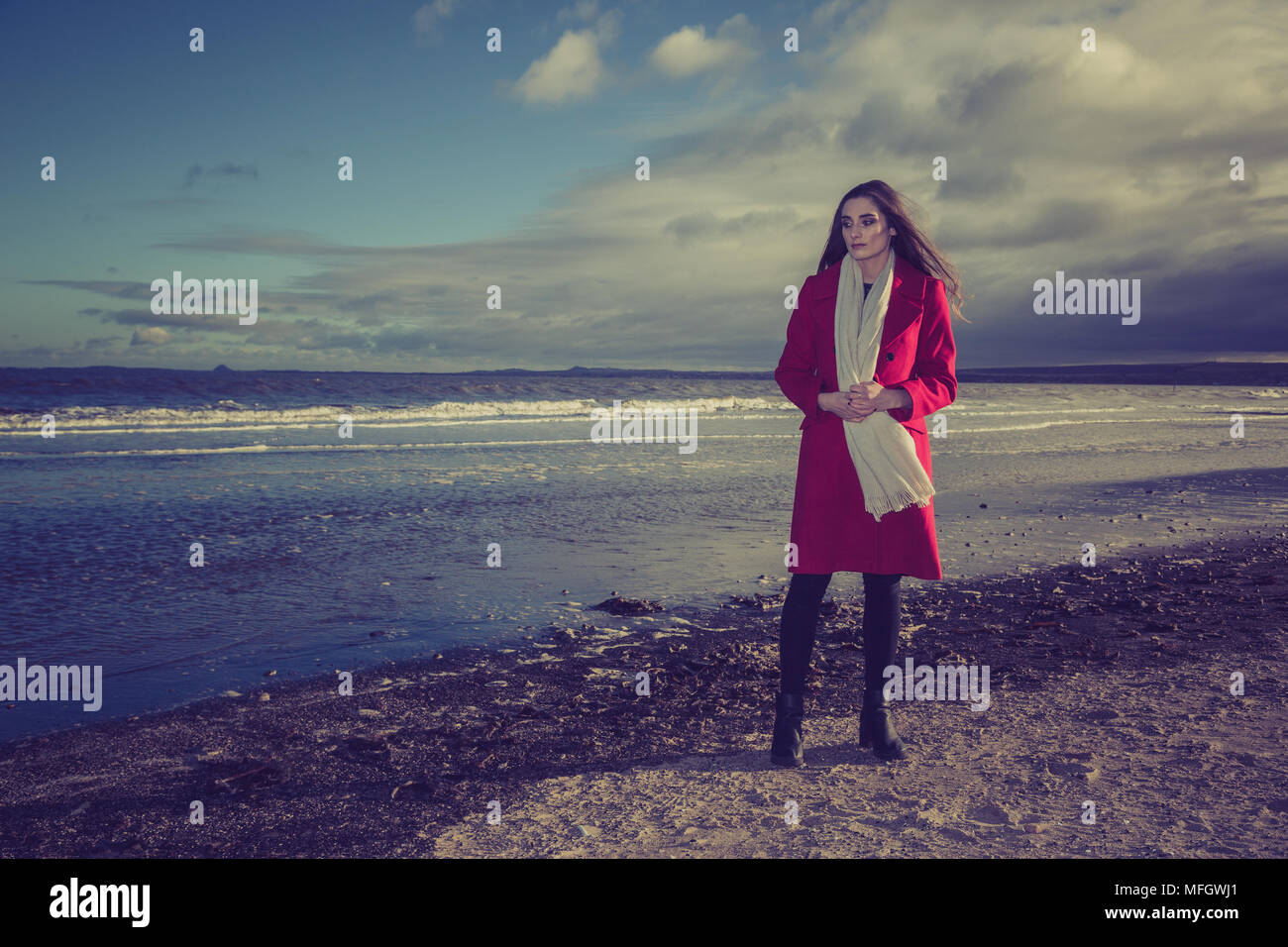 Frau in der roten Jacke an einem Strand. Stockfoto