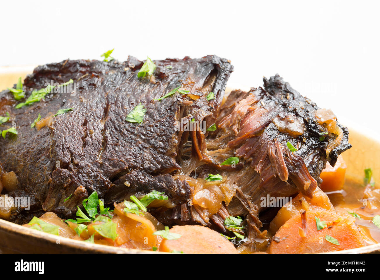 Ein Ochse Wange, die in einem Kupfer Pfanne und dann langsam gekocht in einem Slow Cooker mit Wurzelgemüse und mit gehackter Petersilie garniert angebraten wurde. Stockfoto