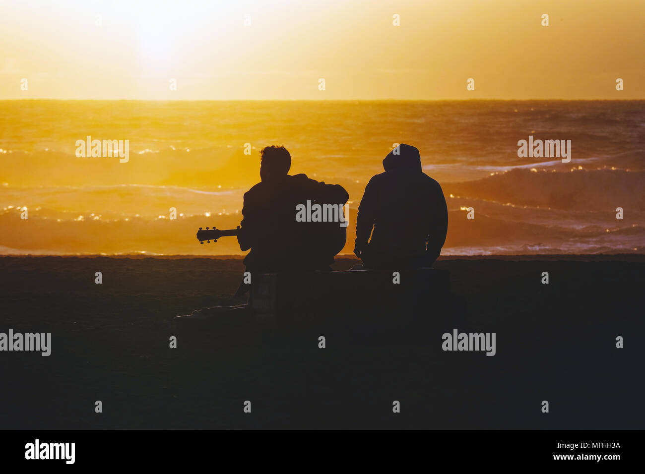 Silhouette der akustischen Gitarre spielen Musiker am Ocean Beach in San Francisco, Kalifornien bei Sonnenuntergang. Stockfoto