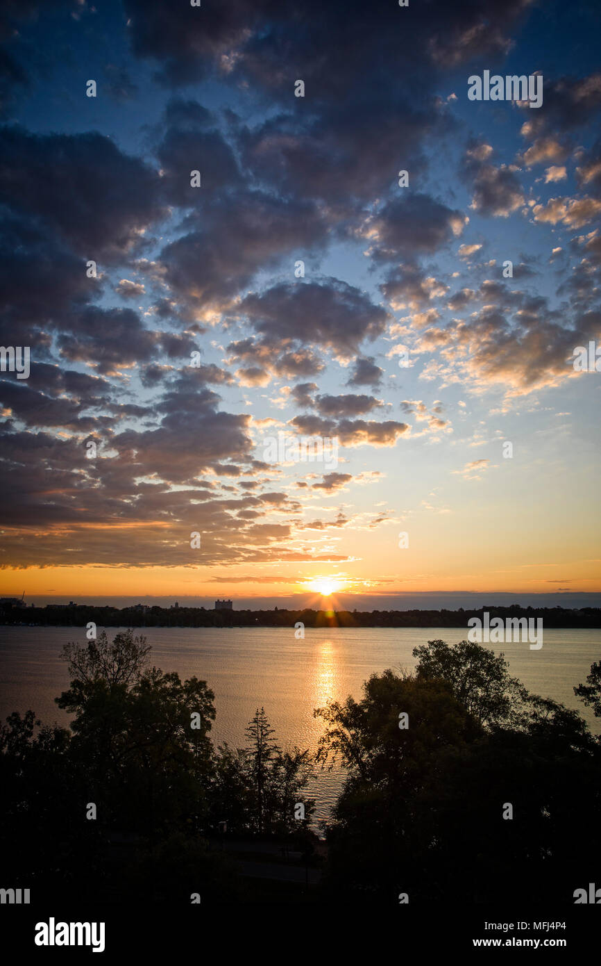 Der Sonnenaufgang bricht den Horizont und spiegelt sich am Lake Calhoun in Minneapolis, Minnesota, wider. Stockfoto