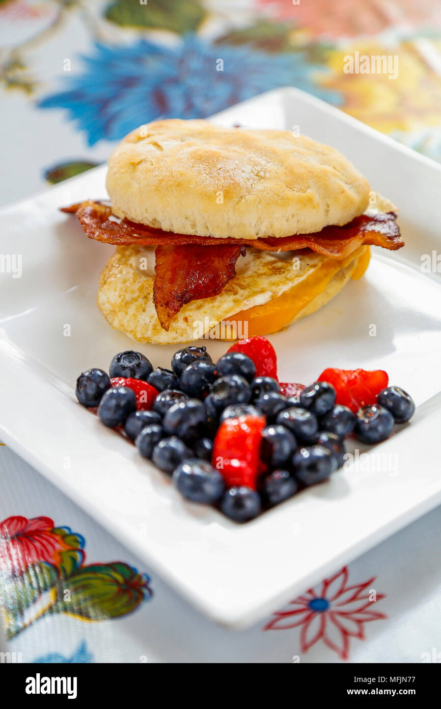 Ein Schinken, Ei und Käse Breakfast Sandwich mit einer Seite der Beeren. Stockfoto