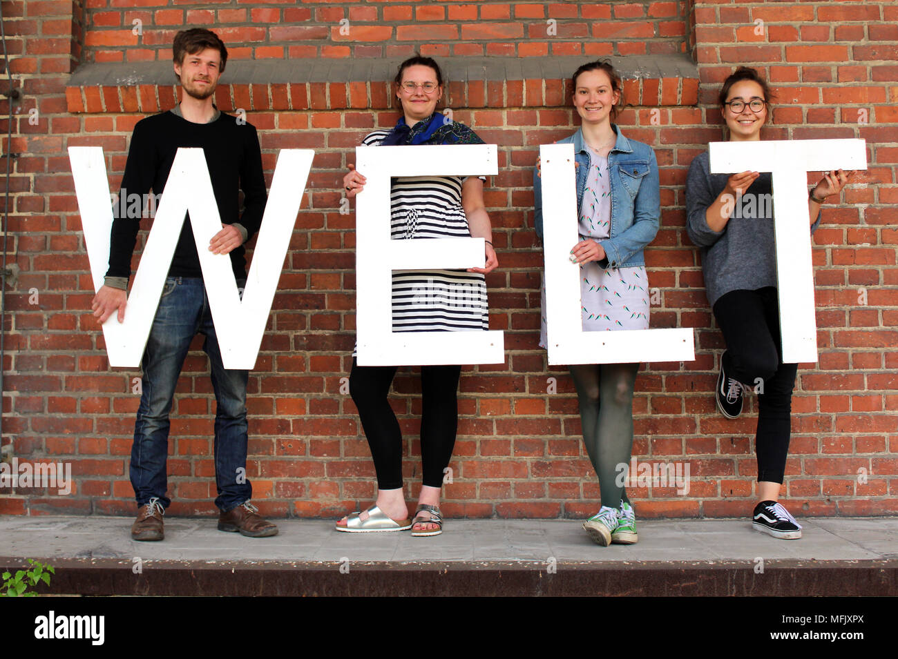 23 April 2018, Deutschland, Görlitz: Studenten Lorenz Kallenbach (L-R), Michaela Krauss, Lisa Schaefer und Josephine Junker Holding die Buchstaben, die das Wort 'Welt' (Lit. Welt). Die Studenten und junge Künstler organisieren die Ausstellung 'Weltstadt' (lit. Welt Stadt Görlitz) in einem leeren Güterbahnhof. Foto: Miriam Schönbach/dpa-Zentralbild/dpa Stockfoto