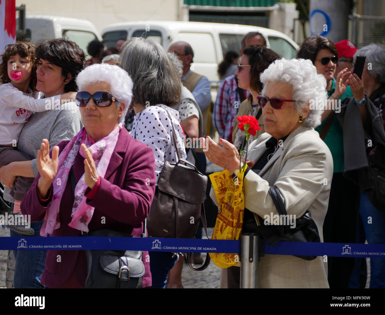 Lissabon, Portugal, 25. April 2018: Die Menschen in den Straßen von der beliebte Stadtteil Almada gesehen, in Lissabon (Portugal), wie sie sich an den Feierlichkeiten zum 44. Jahrestag des Nelken Revolution nehmen. Bei dieser Gelegenheit, jungen und alten Menschen, Mitglieder der retrired, Sport ou Musik Verbände, Verunreinigen auf der Straße, das Tragen der roten Kappen und mit roten Nelken Hommage an die Revolution 1974 die Gedrivet der alten Rechten diktatorischen Regimes von António de Oliveira Salazar zu bezahlen. Credit: Serge Mouraret/Alamy leben Nachrichten Stockfoto