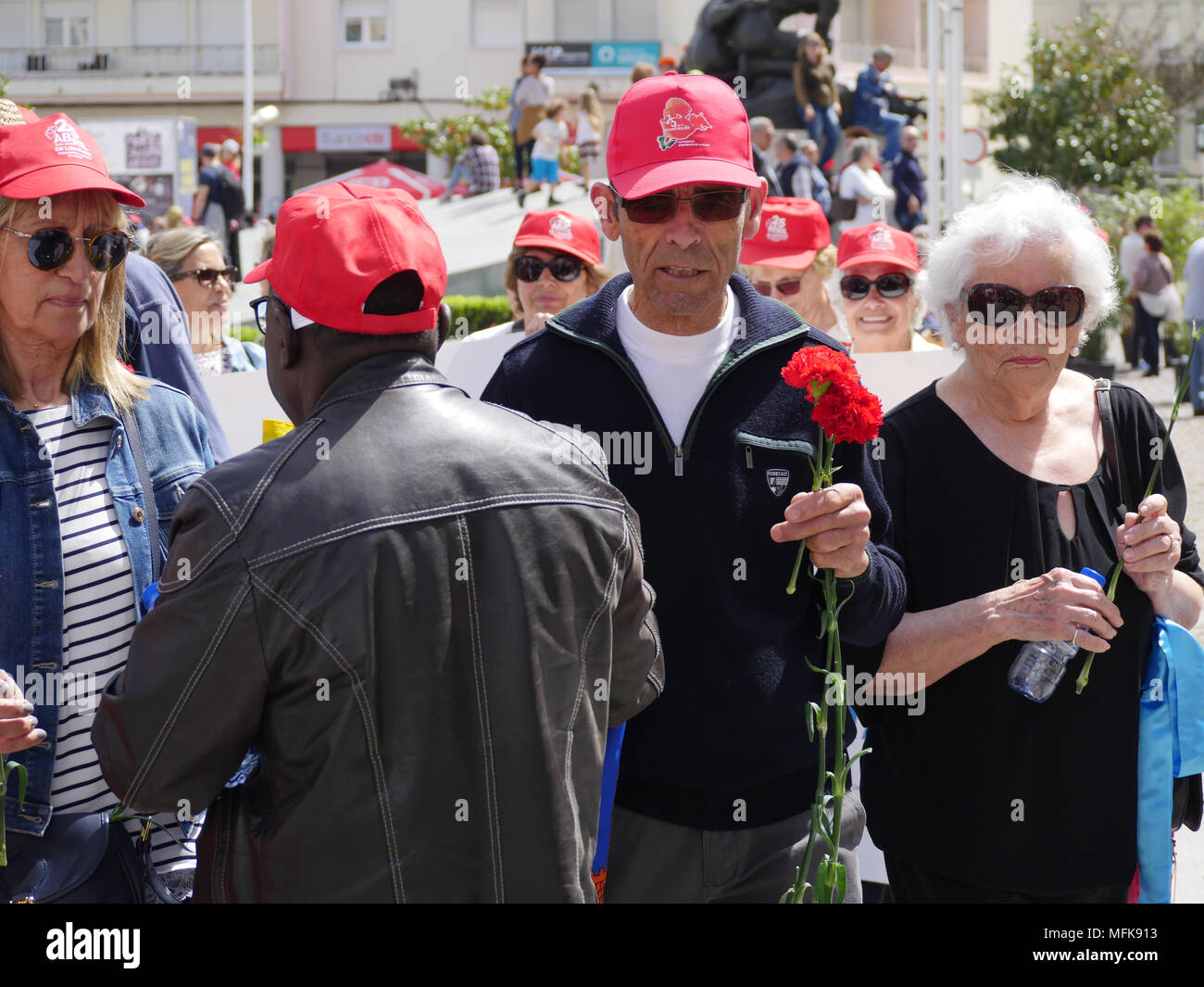 Lissabon, Portugal, 25. April 2018: Die Menschen in den Straßen von der beliebte Stadtteil Almada gesehen, in Lissabon (Portugal), wie sie sich an den Feierlichkeiten zum 44. Jahrestag des Nelken Revolution nehmen. Bei dieser Gelegenheit, jungen und alten Menschen, Mitglieder der retrired, Sport ou Musik Verbände, Verunreinigen auf der Straße, das Tragen der roten Kappen und mit roten Nelken Hommage an die Revolution 1974 die Gedrivet der alten Rechten diktatorischen Regimes von António de Oliveira Salazar zu bezahlen. Credit: Serge Mouraret/Alamy leben Nachrichten Stockfoto