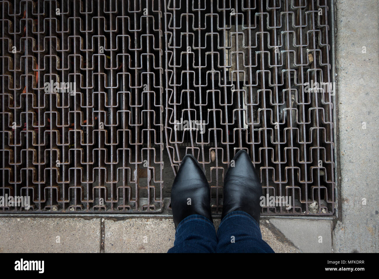 Eine Person, die Spitzen tragen toed Stiefel stehend auf einem Bürgersteig Gitter Stockfoto