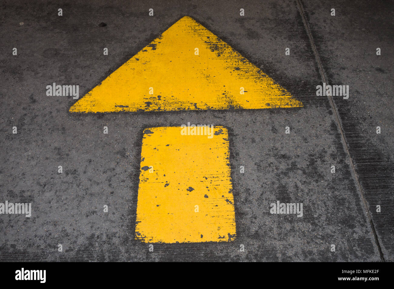 Ein grosser gelber Pfeil auf einem Zement Bürgersteig lackiert Stockfoto