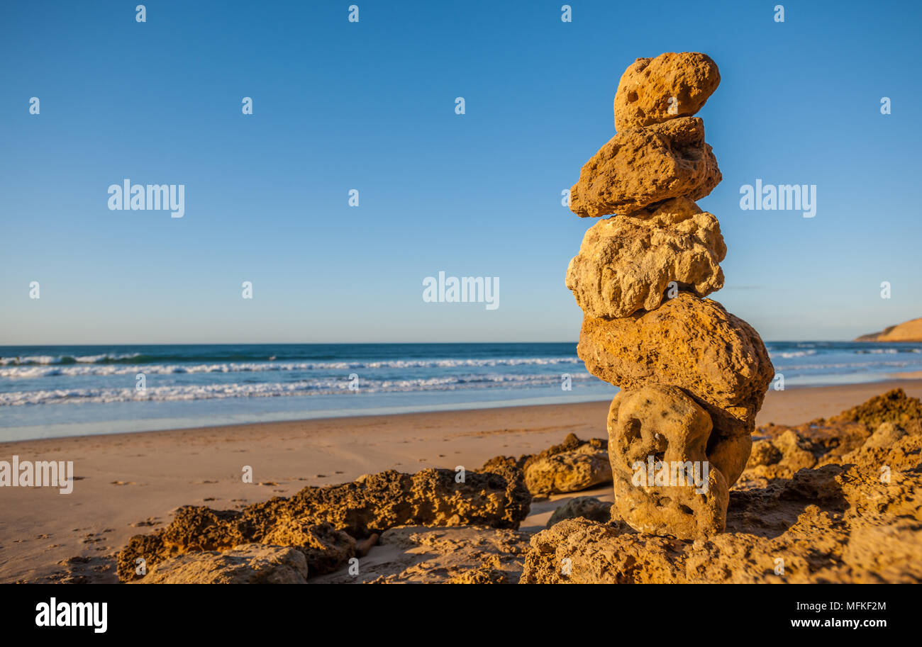 Ein Stapel von fünf kleinen Felsen, die sich an einem sonnigen Strand balancieren Stockfoto