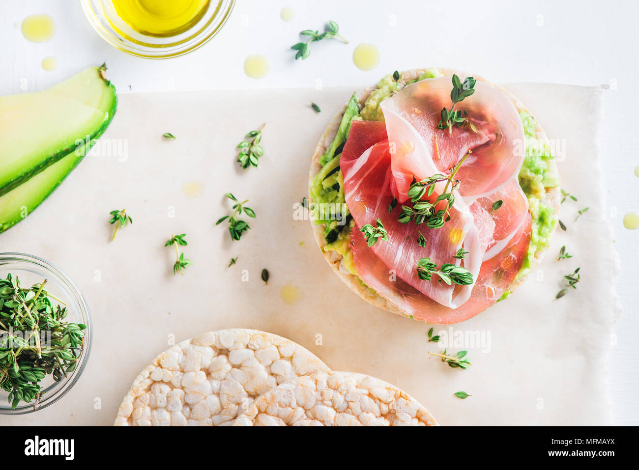 Knäckebrot gesunden Snack mit Parma Schinken, Avocado, Olivenöl, Thymian. Einfaches Frühstück close-up auf weißem Hintergrund mit kopieren. Stockfoto