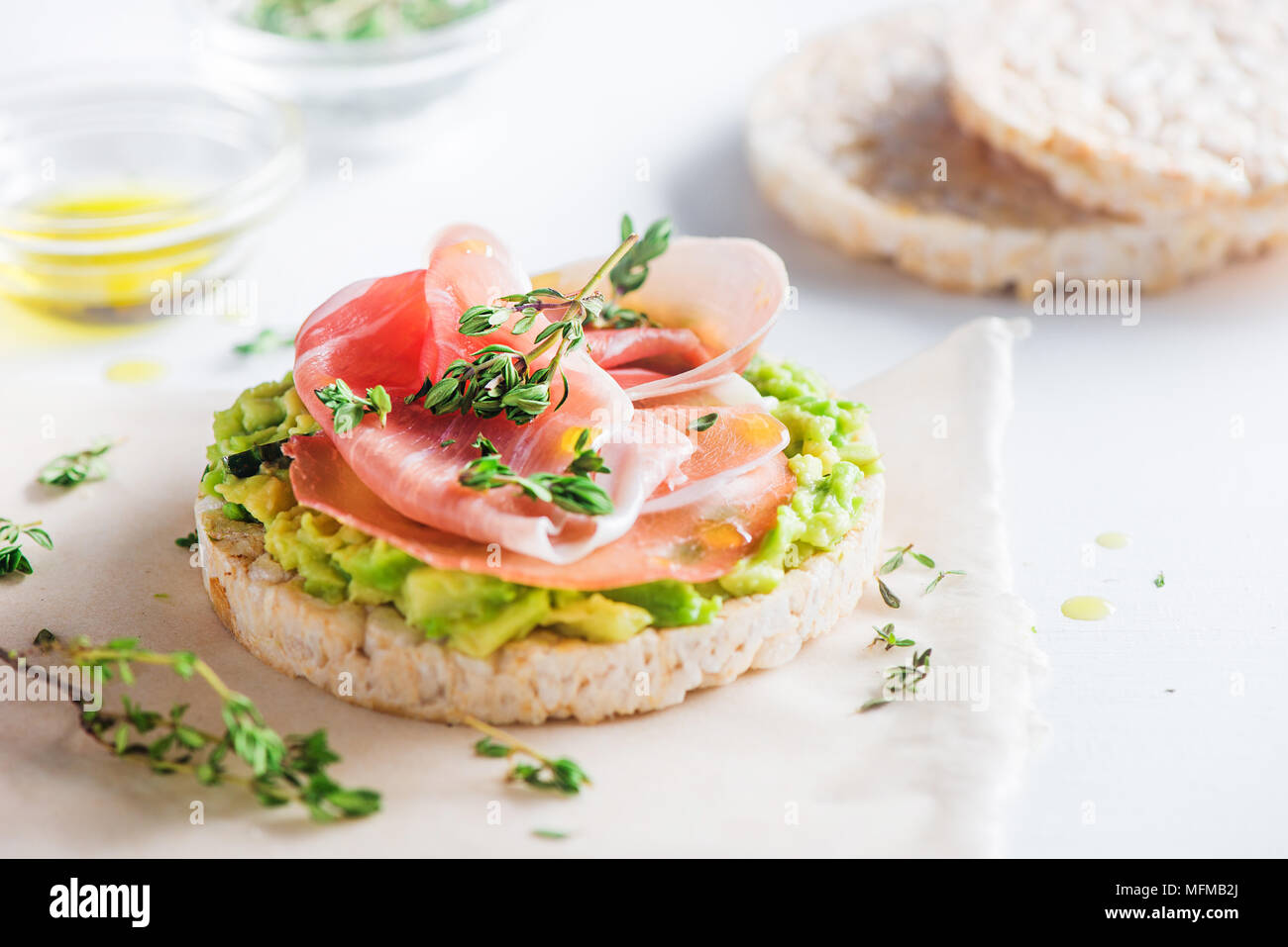 Knäckebrot gesunden Snack mit Parma Schinken, Avocado, Olivenöl, Thymian. Einfaches Frühstück close-up auf weißem Hintergrund mit kopieren. Stockfoto