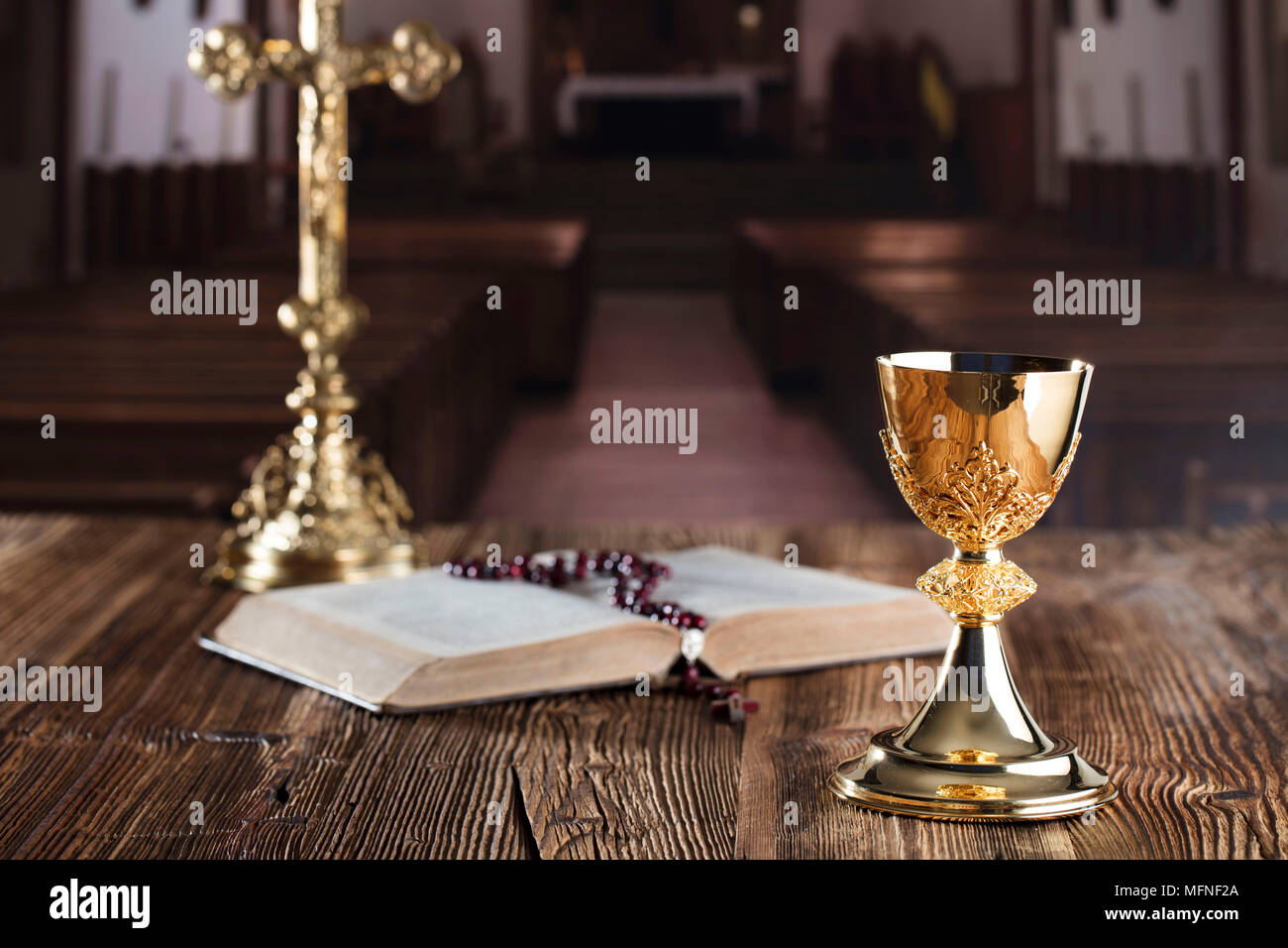 Die erste heilige Kommunion. Das Kreuz, Bibel, Rosenkranz und goldenen Kelch auf braunem Hintergrund. Stockfoto