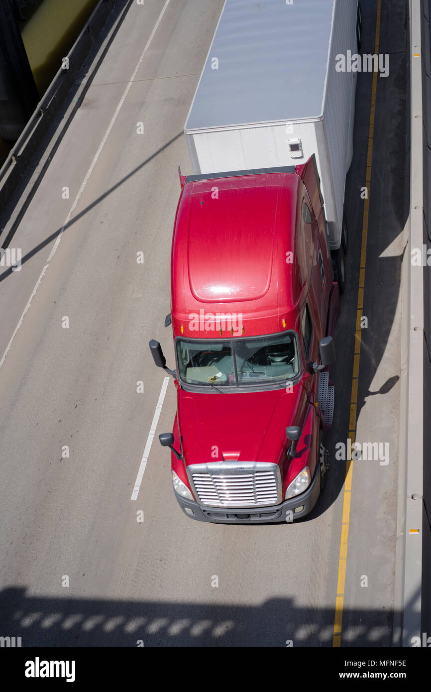 Big Rig red American Semi Truck Transport von kommerziellen Ladung trocken van Auflieger unter Drehen überführung Straße Kreuzung entlang des Flusses Stockfoto