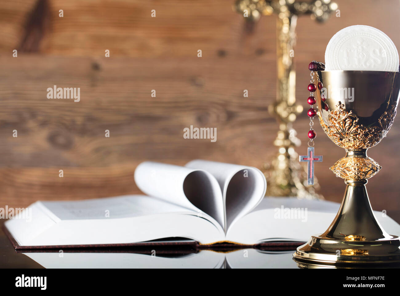 Die erste heilige Kommunion. Das Kreuz, Bibel, Rosenkranz und goldenen Kelch auf braunem Hintergrund. Stockfoto