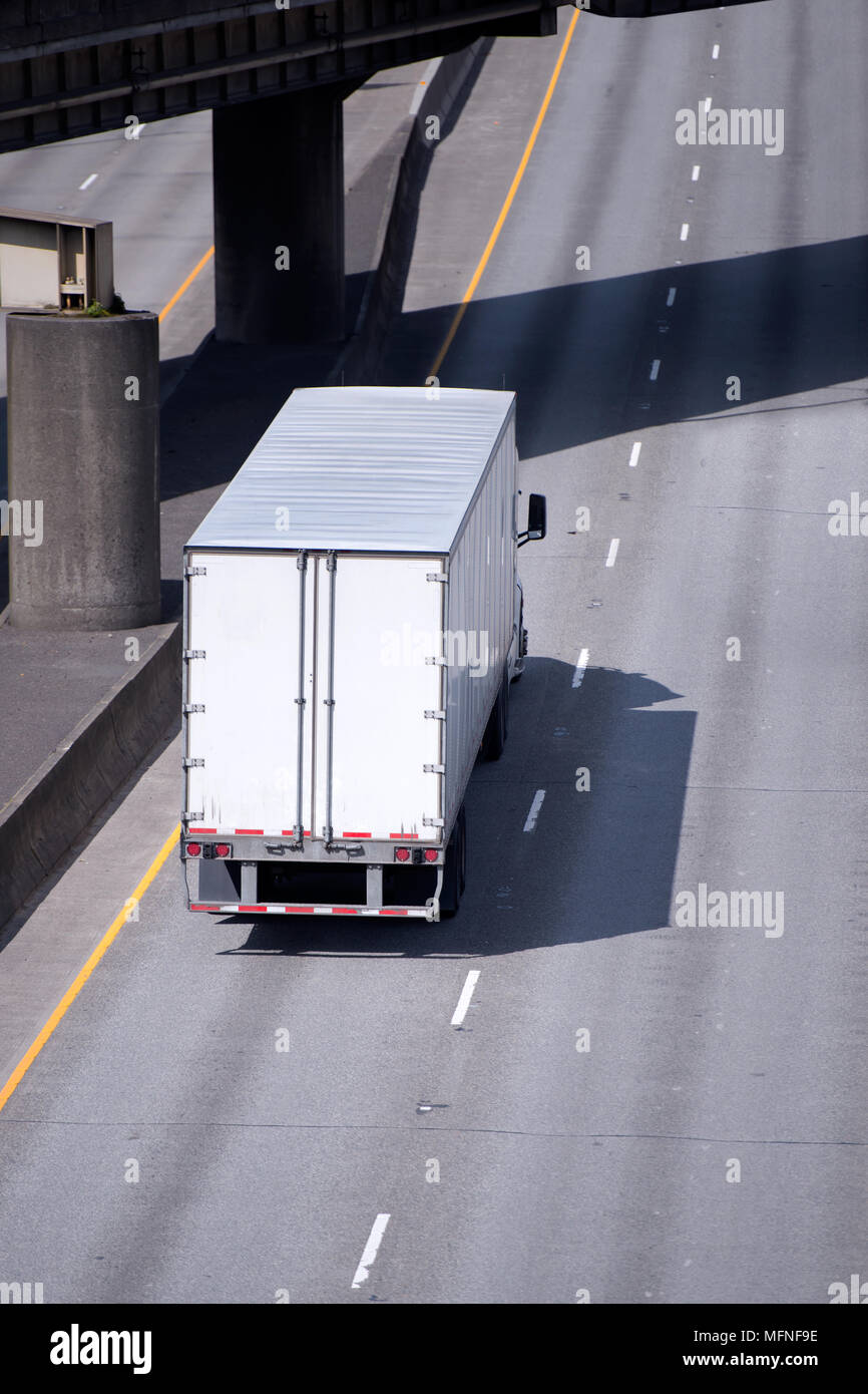 Big Rig white American Semi Truck Transport von kommerziellen Ladung in semi Trailer unter multilevel Überführung Straßen Kreuzung gehen mit Unterstützung der Säule Stockfoto