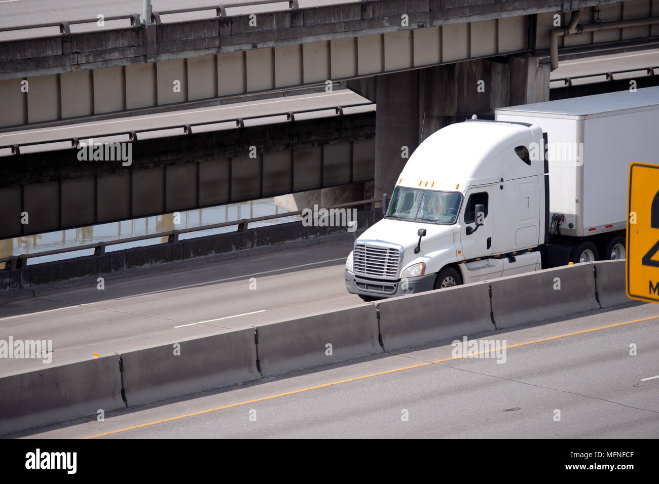 Big Rig white American Semi Truck Transport von kommerziellen Ladung trocken van Auflieger gehen unter multilevel Überführung Straßen Kreuzung alo Stockfoto