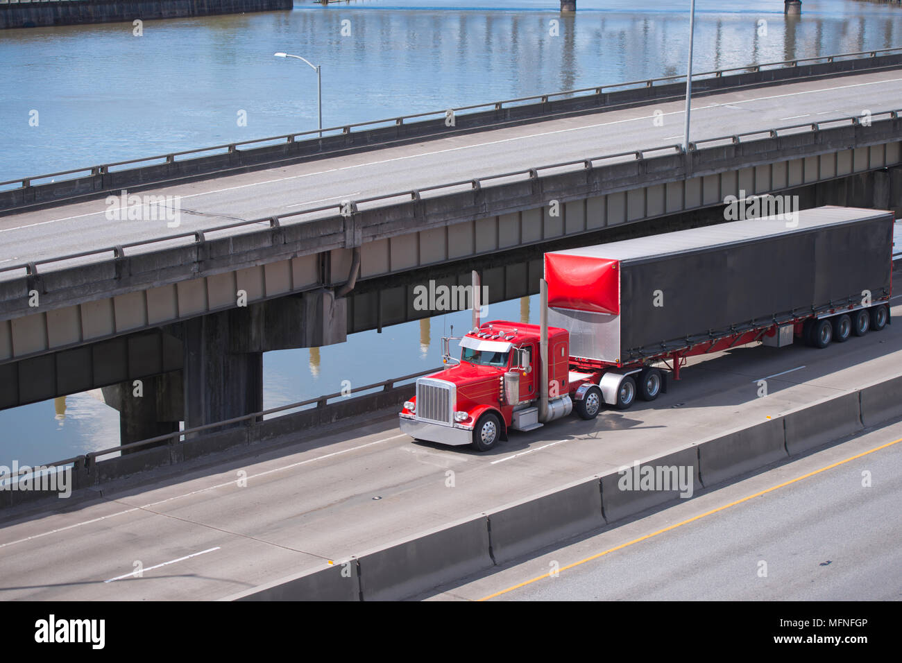 Big Rig red Classic American Semi Truck Transport von kommerziellen Ladung trocken van Auflieger gehen unter multilevel Überführung Straßen intersecti Stockfoto