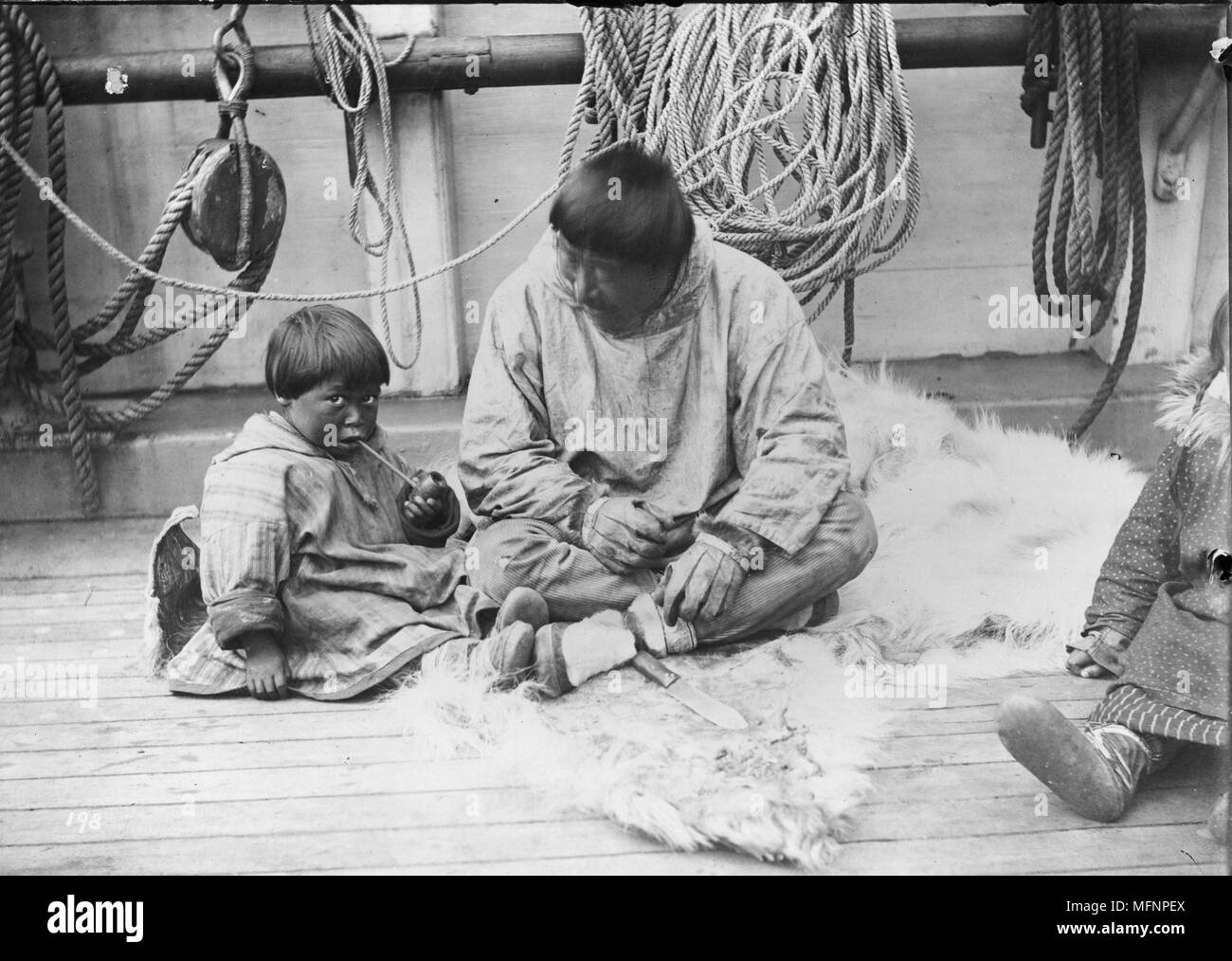 Native American Kind und Mann sitzt an Deck eines Schiffes, möglicherweise das Zollboot 'Bär' während einer Reise Whalers aus der Alaska Küste, 1897 zu retten. Der Mensch ist Kind, wie Rauch ein Rohr. Dr. Samuel J. Call (1858-1909) Stockfoto