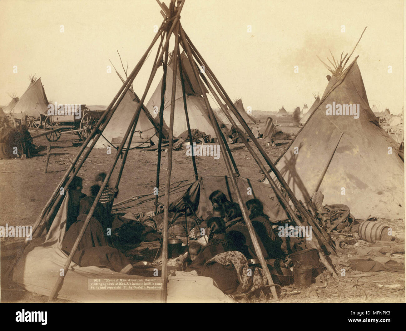 Oglala Frauen und Kinder in einem Unbedeckten tepee Frame in einem Feldlager sitzen - die meisten sind auf der Suche von der Kamera entfernt - wahrscheinlich auf oder in der Nähe von Pine Ridge Reservat. 1891. Foto von John C.H.Grabill (1887-1891). Stockfoto