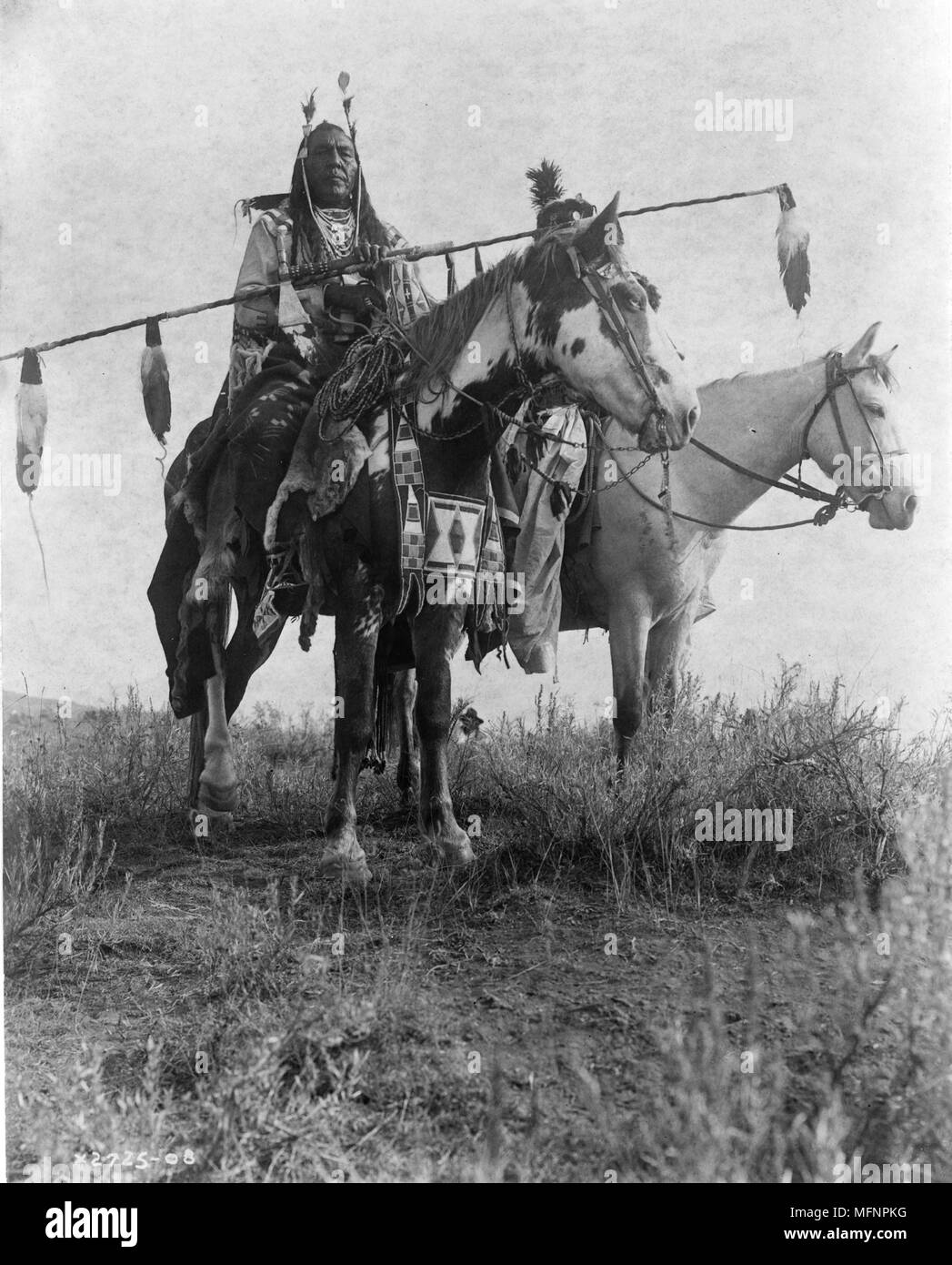 Dorf criers auf dem Pferd, Vogel auf dem Boden und Gegabelten Bügeleisen, Crow Indianern, Montana, 1908 Foto von Edward Curtis (1868-1952). Stockfoto