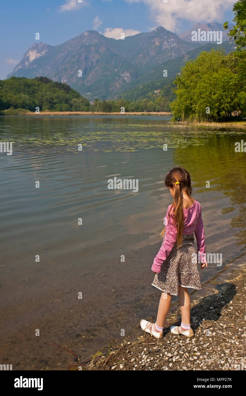 Ein sieben Jahre altes Mädchen ist bei einem Morgen an einem kleinen See in Italien Stockfoto