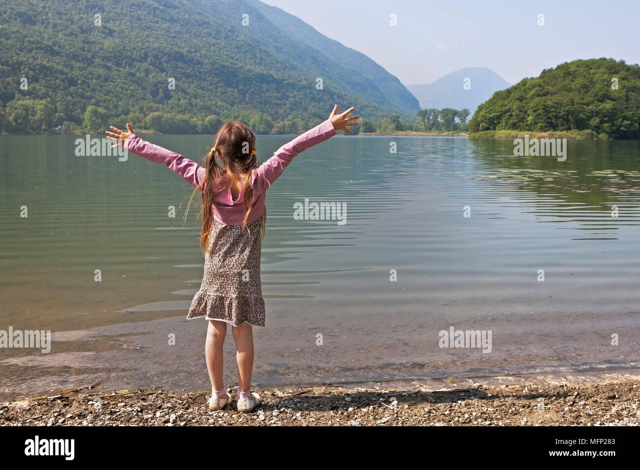 Ein sieben Jahre altes Mädchen ist bei einem Morgen an einem kleinen See in Italien Stockfoto
