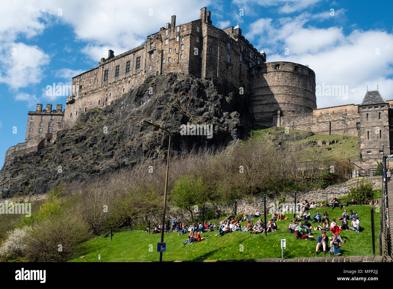 Blick auf die Burg von Edinburgh vom Grassmarket an einem sonnigen Tag und an den Menschen sitzen auf Gras, Altstadt, Edinburgh, Schottland, Großbritannien Stockfoto