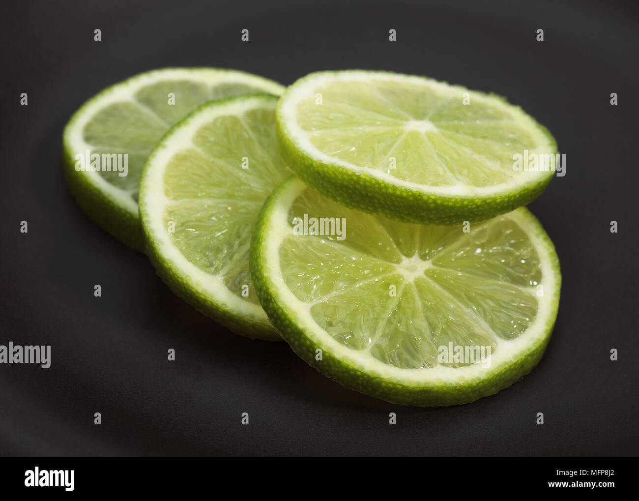 Grüne Zitrone, Citrus aurantifolia auf schwarzem Hintergrund Stockfoto