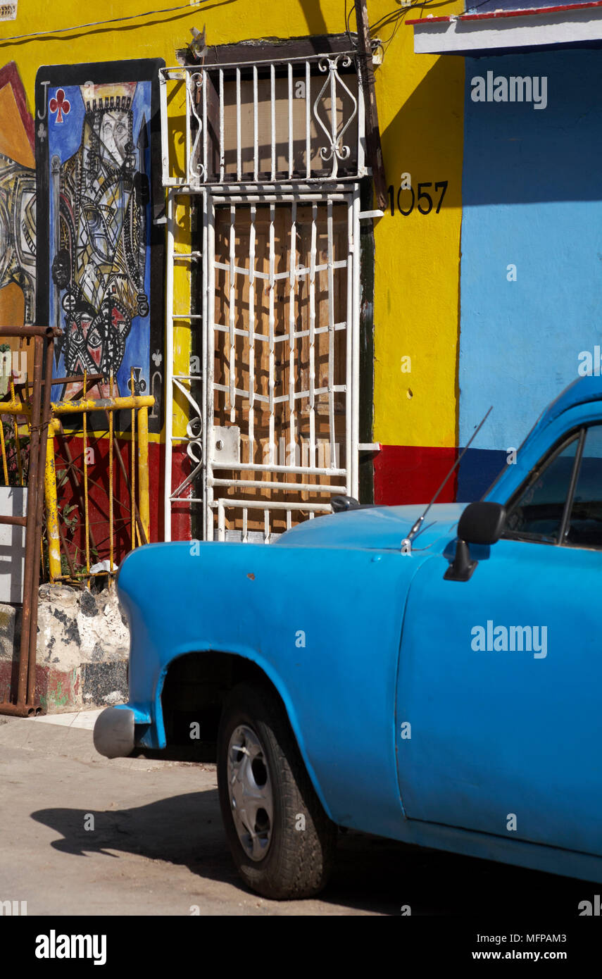 Altes blaues Auto in der Straße geparkt mit Kunstwerken malte auf Gebäude in Havanna, Kuba, Karibik, Karibik, Zentral- und Südamerika. Stockfoto