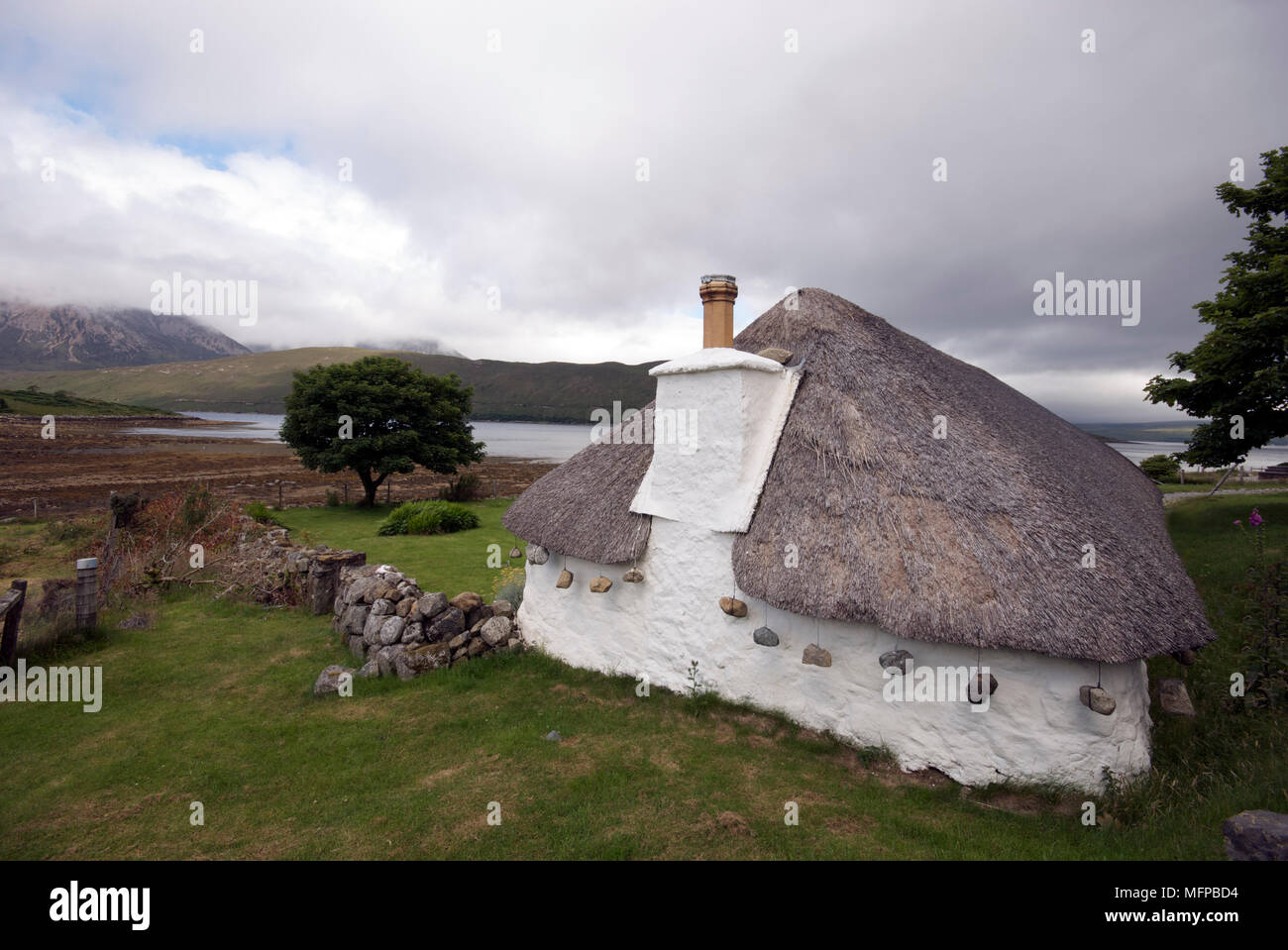 Traditionelle, historische Haus mit Strohdach und Steinen, auf der Isle Of Skye mit Blick auf Loch Ainort hängen. Stockfoto