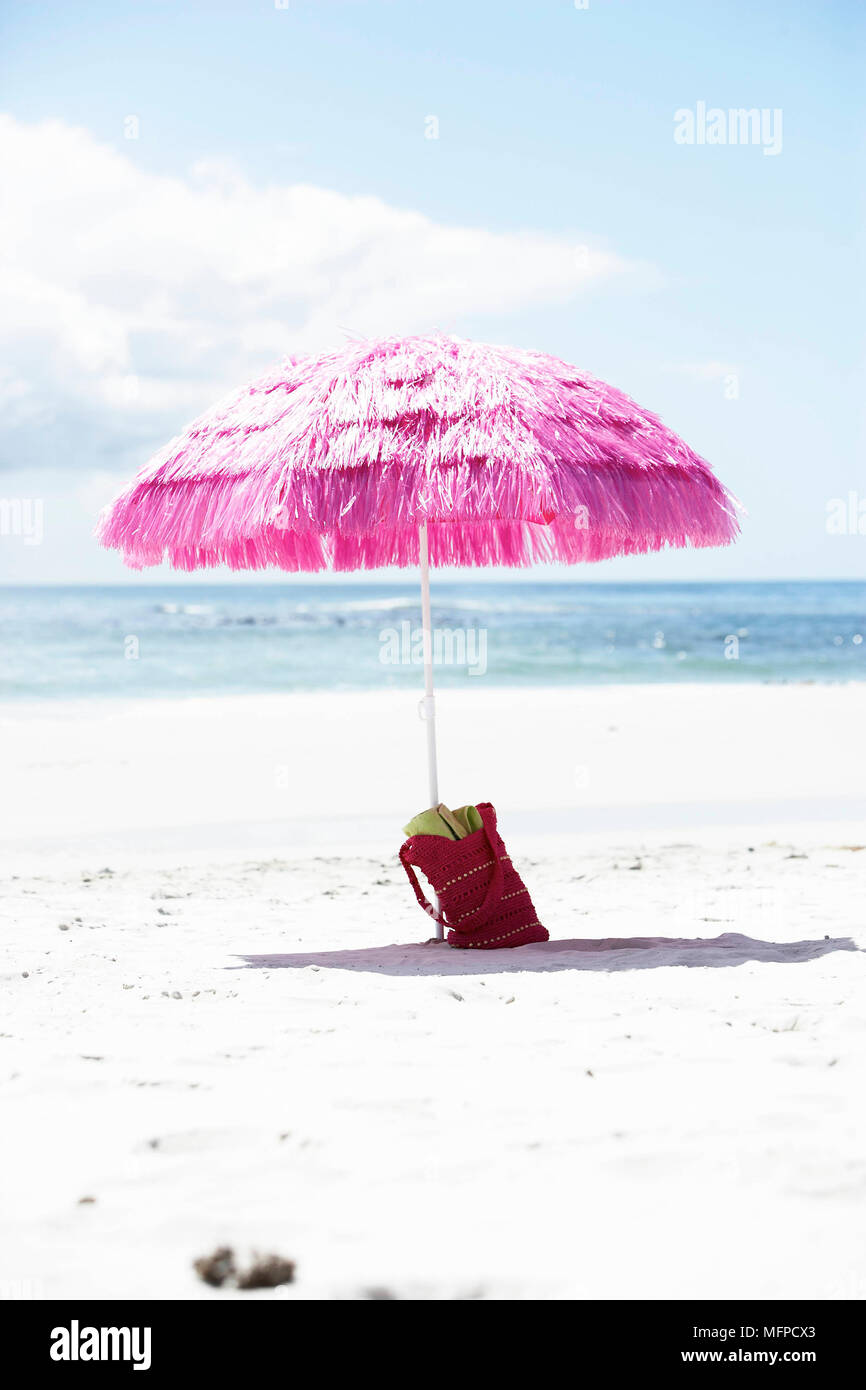 Tasche an der Basis der rosa Sonnenschirm am Strand Stockfotografie - Alamy