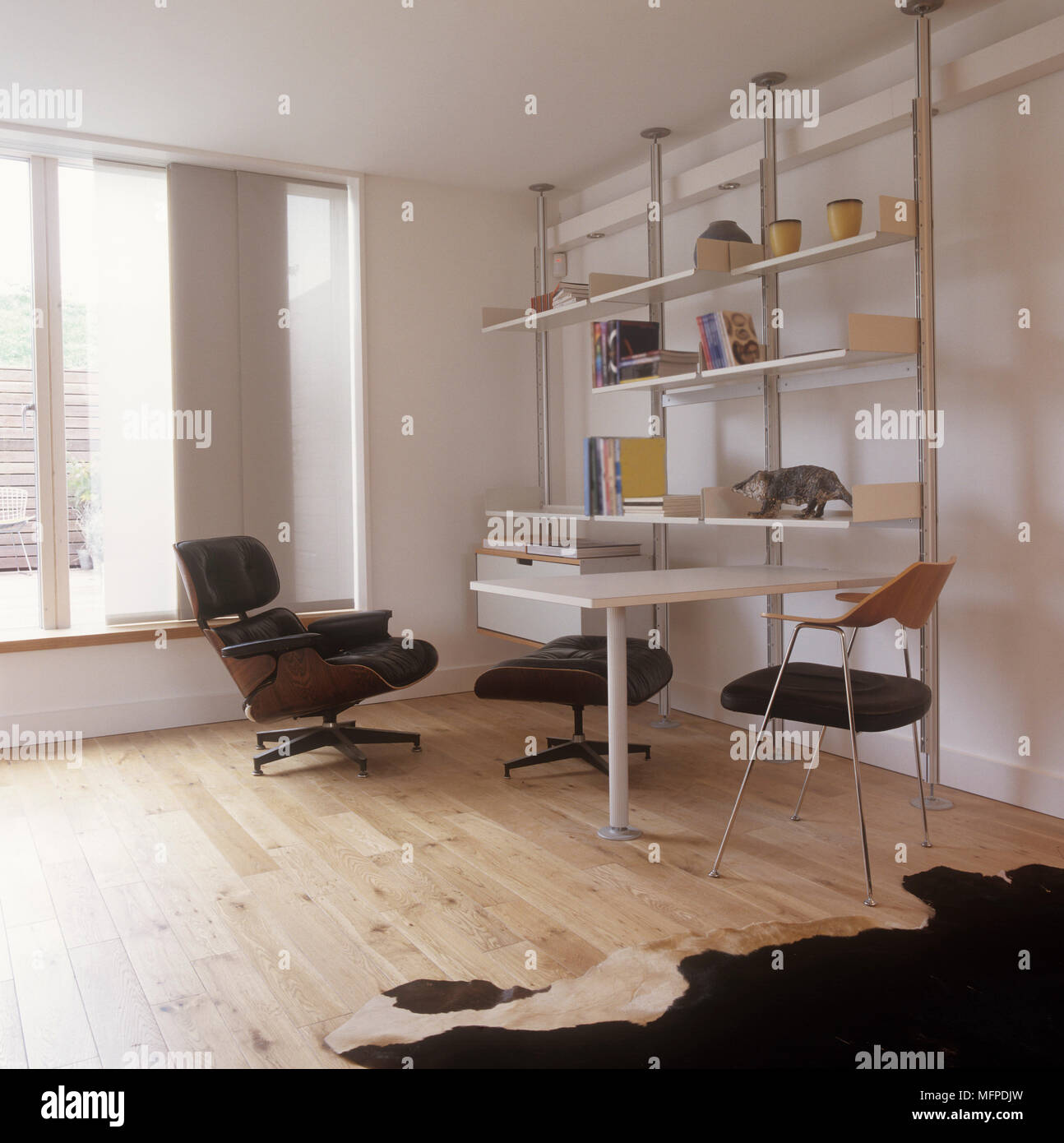 Home Office mit Regalen, einem Tisch und Stühlen, Holzfußboden und eine Wolldecke. Stockfoto